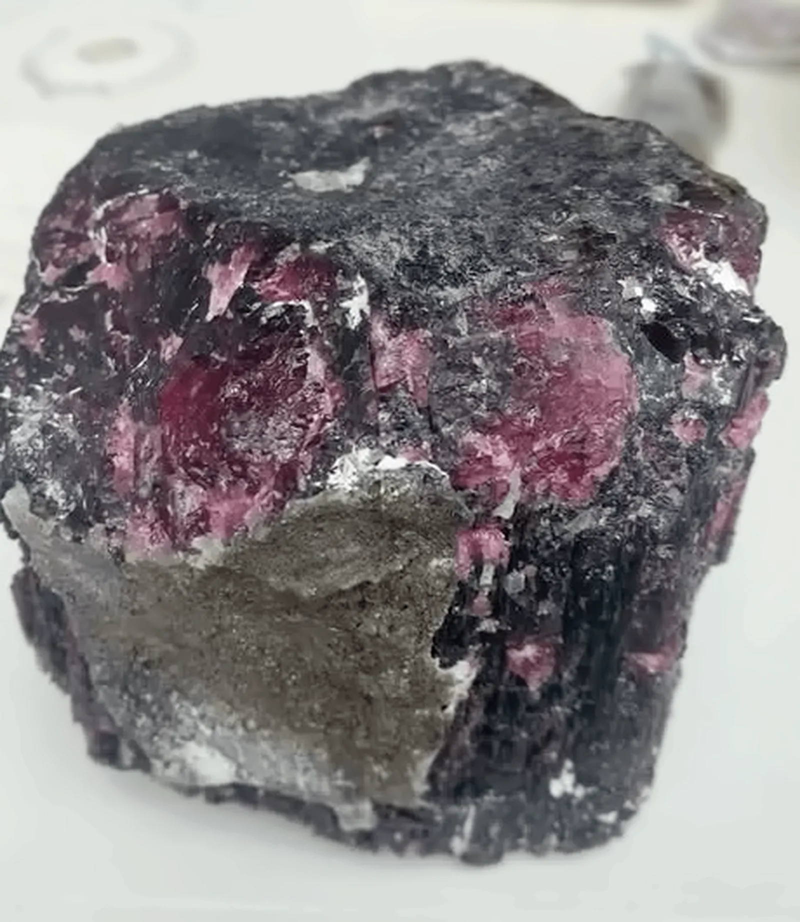 A block of dark matrix rock with deep red ruby crystals set through it.