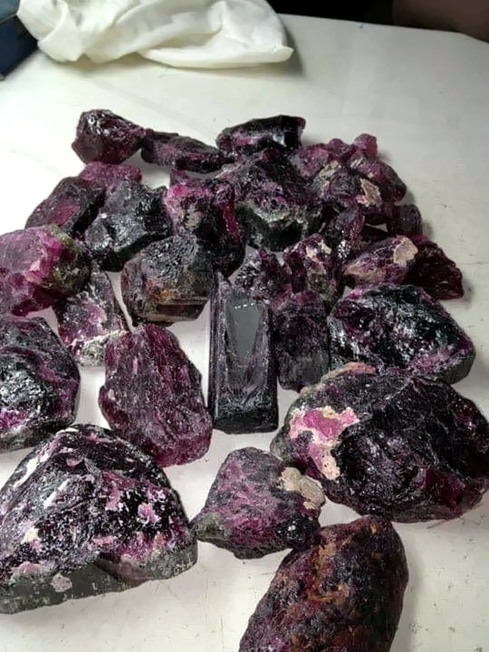 A parcel of unsorted rough ruby laid out on a white table.